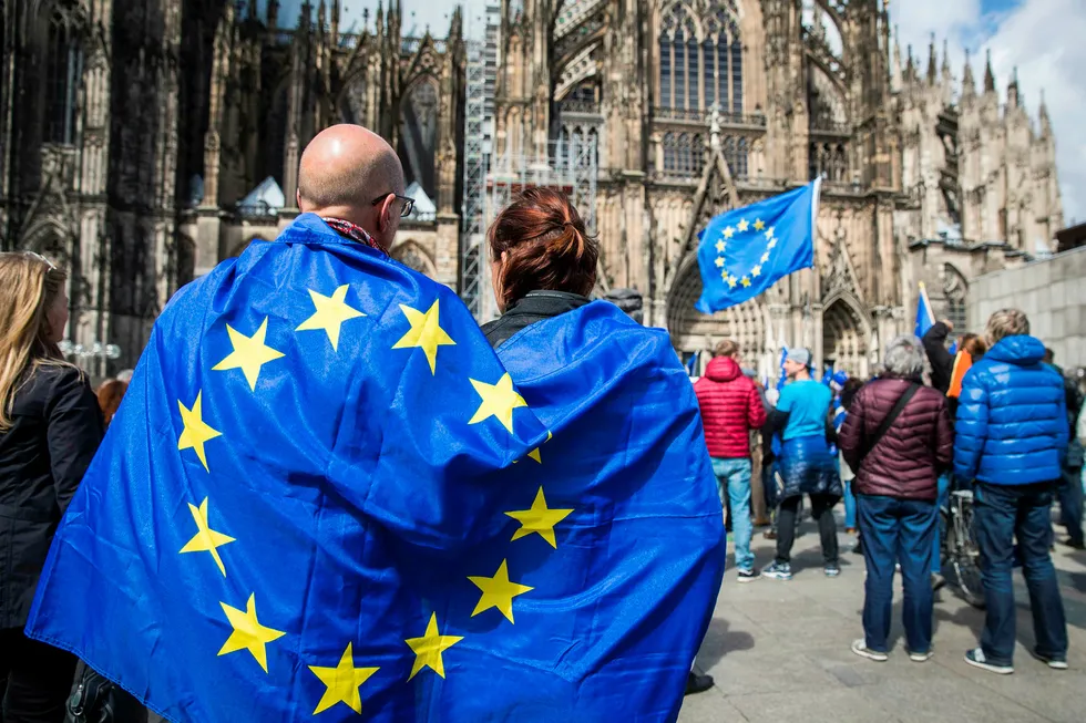 Pro EU activists are seen covered with an EU flag during a _Pulse of Europe_ rally outside the Cathedral in Cologne, western Germany, on April 23, 2017. / AFP PHOTO / Odd ANDERSEN Foto: ODD ANDERSEN