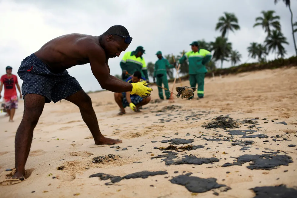 A resident works to remove an oil spill on Barra de Jacuipe beach in Camacari, Bahia state, Brazil