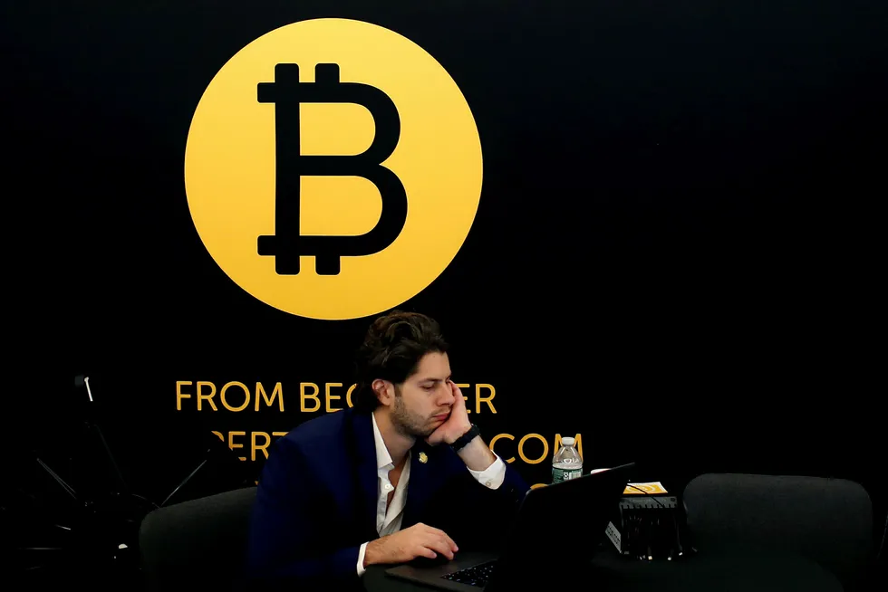 Mange eiere av bitcoin og andre kryptovalutaer har glemt eller mistet pin-kodene som gir adgang til pengene. På bildet sitter en mann ved siden av en bitcoin-logo på en blokkjede-teknologi-konferanse i New York i mai. Foto: Mike Segar/Reuters/NTB Scanpix