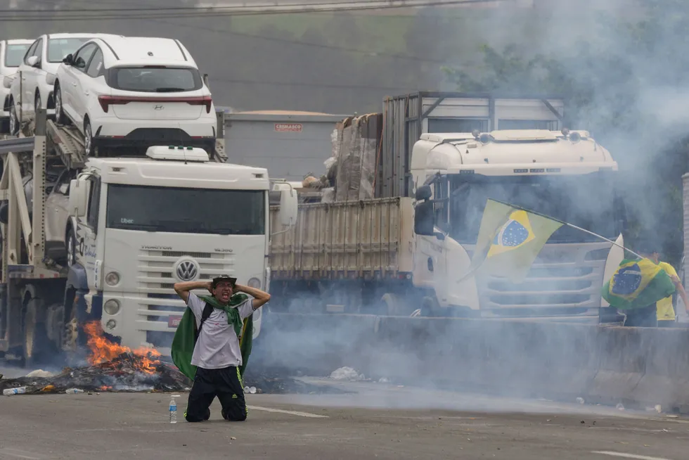 Blockade: a protester kneels with his hands behind his head as riot police launch tear gas at truckers blocking a highway in support of the defeated President Jair Bolsonaro.