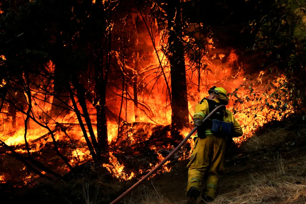 Brannmannskaper arbeider med å slukke en av skogbrannene som har rammet byen Calistoga i California fredag. Foto: Jae C. Hong / AP / NTB scanpix
