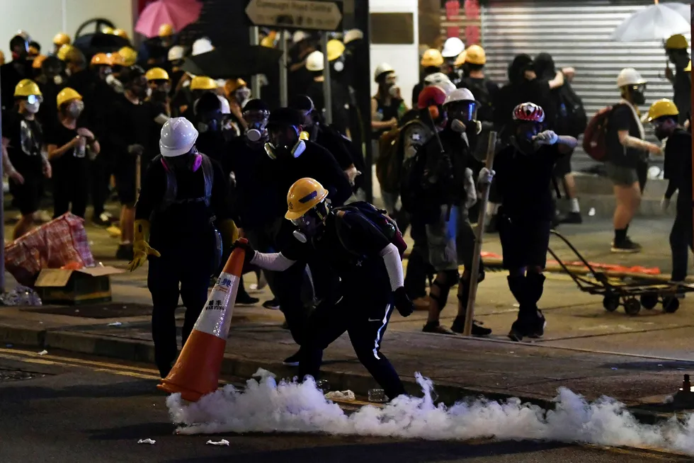 En demonstrant i Hongkong dekker til en boks med tåregass med en trafikkjegle under en av de mange demonstrasjonene som har preget landet de siste månedene.