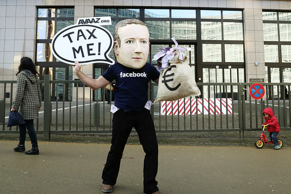 En aktivist med Mark Zuckerberg-maske demonstrerer utenfor EU-hovedkvarteret i Brussel i desember. Sommeren 2018 begynte Facebook å rapportere reklameinntekter i Norge.