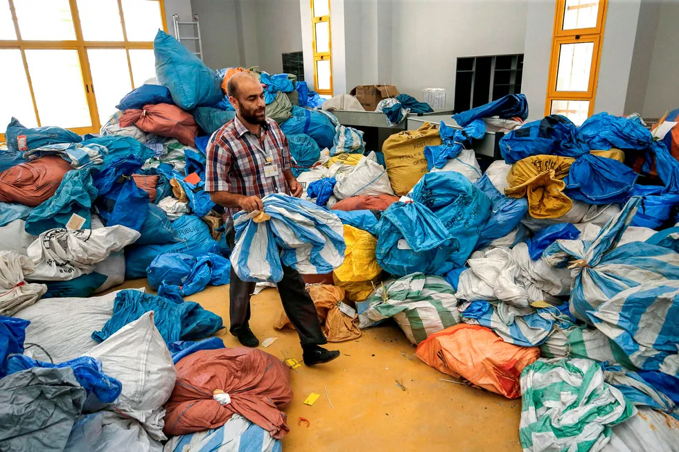 A Palestinian postal worker sifts through sacks of previously undelivered mail dating as far back as 2010, which has been withheld by Israel, at the central international exchange post office in the West Bank city of Jericho on August 14, 2018. – Israel had held the post for years but handed it over to the Palestinian authorities after an agreement. (Photo by ABBAS MOMANI / AFP) ---