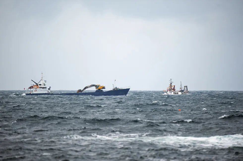 Mindre fiskefartøy i grov sjø utenfor Karmøy, krysser kurs med lasteskip i sandfrakt.