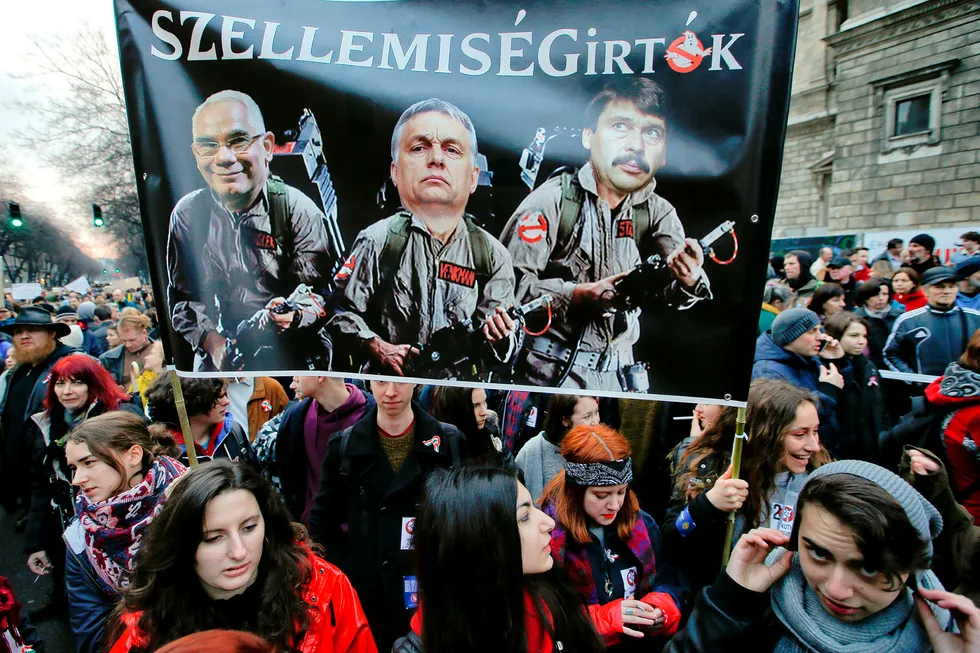 Ungdommer protesterer mot statsminister Viktor Orbán (i midten av plakaten) i Budapest i mars. Bak er Ungarns president Janos Ader (til høyre) og menneskerettighetsminister Zoltan Balog. Foto: Darko Vojinovic/AP/NTB Scanpix