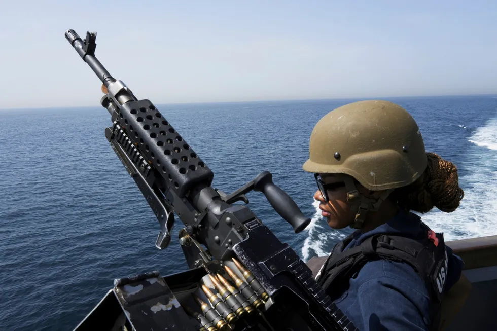 A US Navy service specialist stands guard next to a machine gun aboard the USS Paul Hamilton in the Strait of Hormuz.
