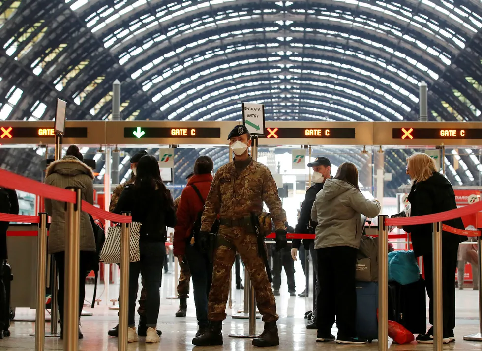 Politi og soldater sjekke passasjerer som forlater Milans hovedtogstasjon. Bildet er tatt mandag 9. mars.