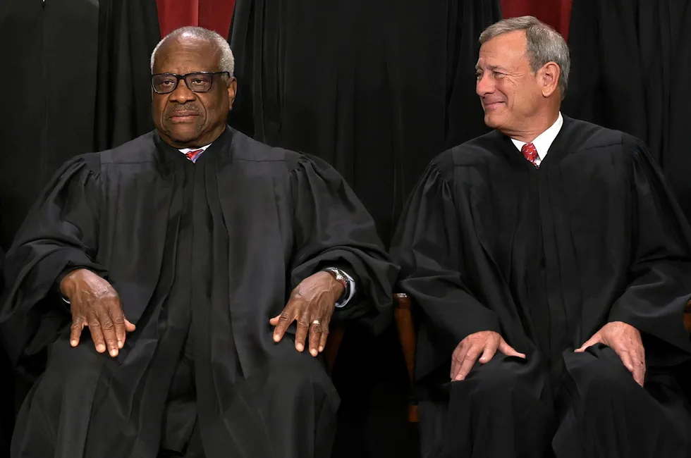 Chief Justice John Roberts looks at his controversial colleague, Associate Justice Clarence Thomas, while posing for photographs.