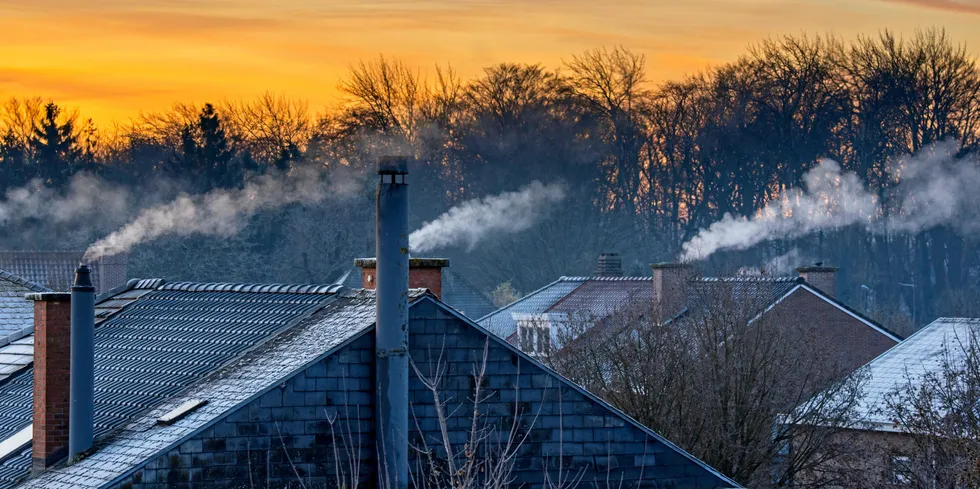 Smoking domestic rooftop chimneys from houses emitting vapour from gas boilers