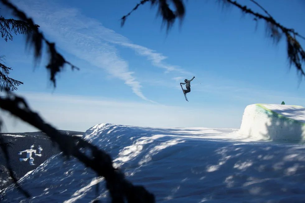 Med utsikt til fakkelmannen griper Tora Johansen de bakre skituppene og svever elegant over Gudbrandsdalens blå himmel. Foto: Thomas T. Kleiven