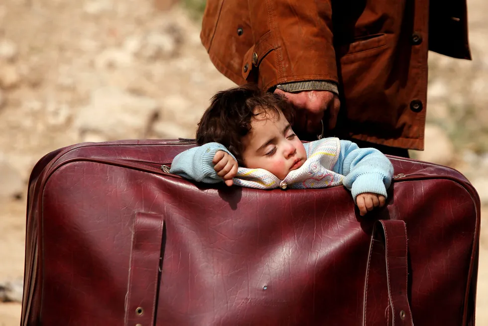 På flukt: Sivilbefolkningen i Syria ble utsatt for krigshandlinger også i 2018. Her sover et barn i en koffert mens folk rømmer fra landsbyen Beit Sawa i midten av mars.