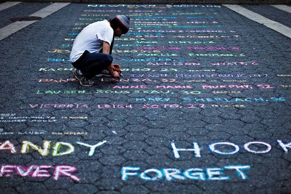 Gatekunstner Mark Panzarino skrev opp navnene til de drepte etter angrepet ved Sandy Hook Elementary School under seksmånedersmarkeringen i New York i 2013. Siden har masseskytingene fortsatt. Foto: Eduardo Munoz/Reuters/NTB Scanpix