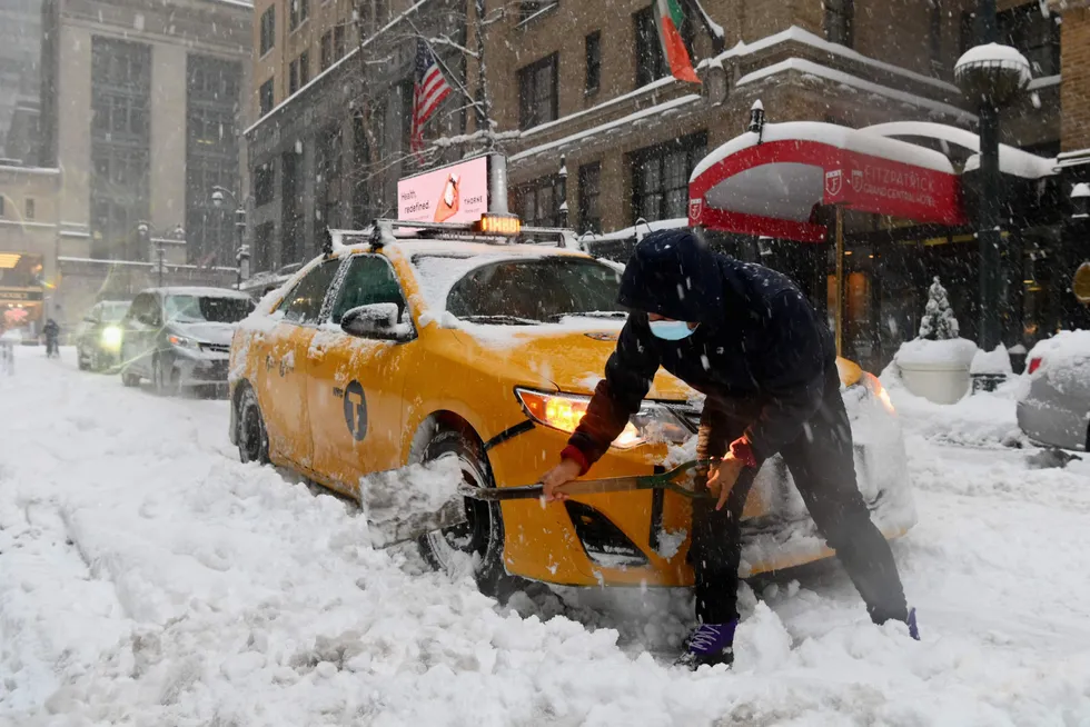 Deep freeze: A New York City taxi cab driver digs out of heavy snow during a winter storm