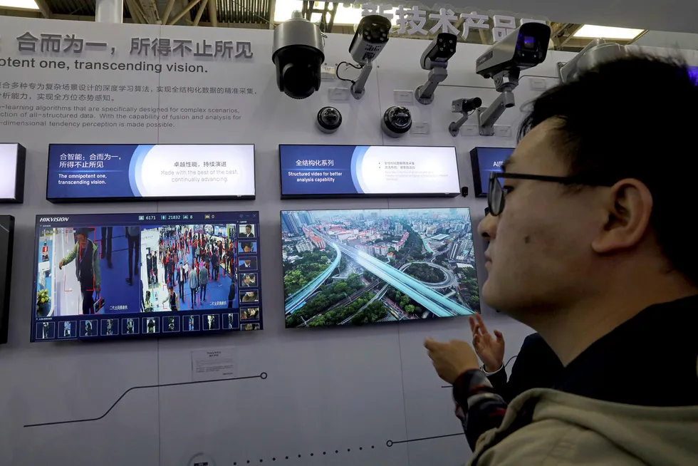 An attendee look at technologies from state-owned surveillance equipment manufacturer Hikvision on a monitor at Security China 2018 in Beijing, China, Tuesday, Oct. 23, 2018. One of China's largest distribution and procurement event for security equipment and services, Security China 2018 attracts hundreds of exhibitors from China and abroad showcasing the latest advancement in surveillance and security technologies. (AP Photo/Ng Han Guan)
