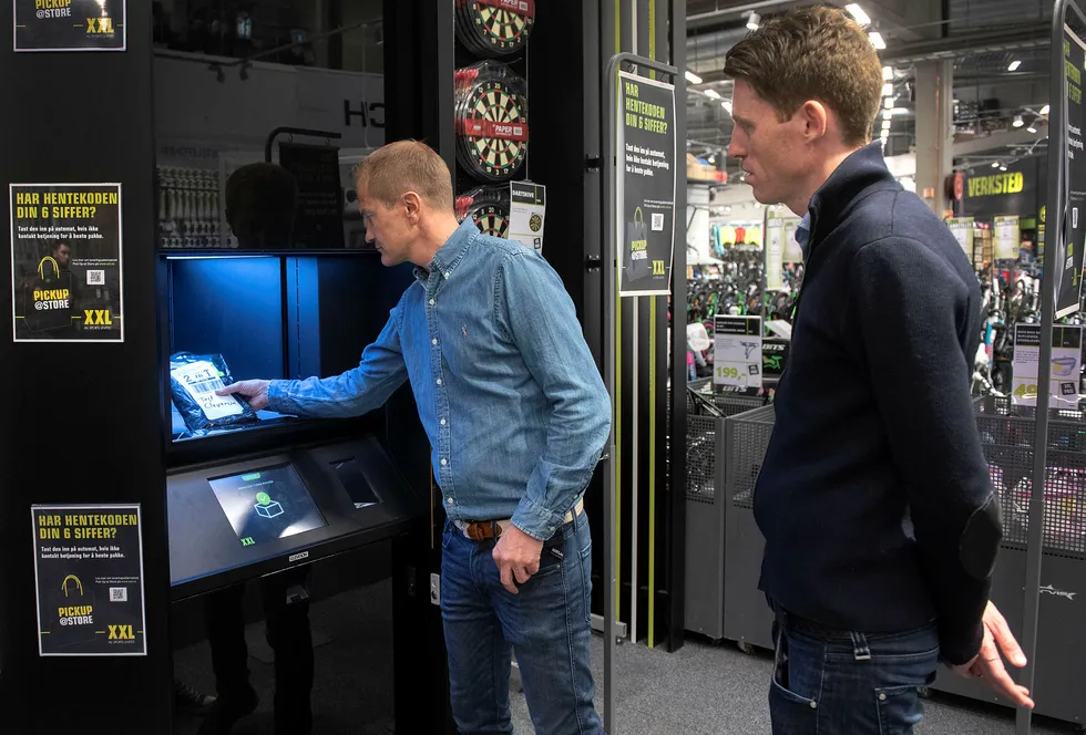 Klikk og hent er i ferd med å bli stor business for kjeder som XXL. Her viser it-direktør Espen Terland og XXL-sjef Tolle Grøterud (til høyre) hvordan pakkene kommer ut fra den nye roboten i butikken på Alnabru.