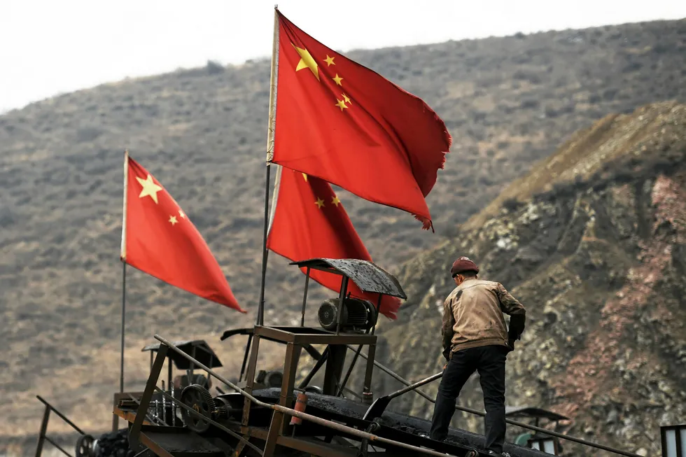 Workflow: Chinese flags fly as a worker clears a conveyer belt on a Shanxi coal mine. The province can now licence companies to explore for CBM as well as coal