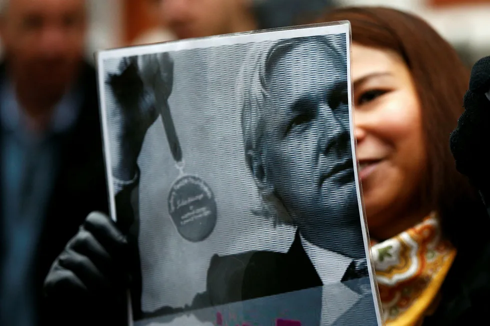 En Julian Assange-tilhenger holder opp en plakat av ham i Ecuador mandag. Foto: PETER NICHOLLS