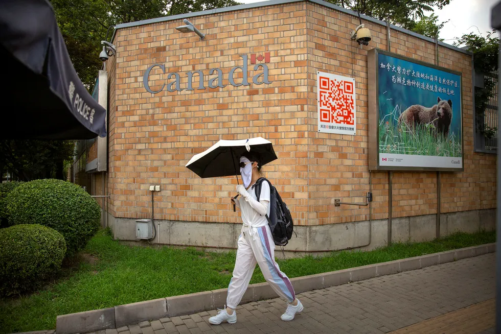 En kvinne iført munnbind går forbi Canadas ambassade i Beijing torsdag, samme dag som en kanadisk statsborger ble dømt til døden.