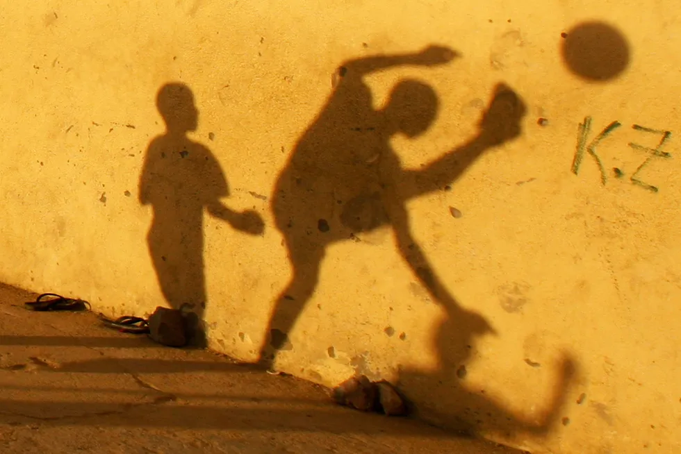 In play: the shadows of children playing soccer are seen on a street wall in Benguela city, Angola