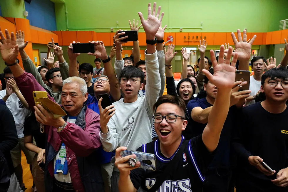 Tilhengere av den pro-demokratiske kandidaten Angus Wong jubler etter at han vant i sitt distrikt i lokalvalget i Hongkong søndag. Ifølge de foreløpige resultatene utklasser de pro-demokratiske kandidatene de mer Beijing-vennlige kandidatene. Foto: AP / NTB scanpix