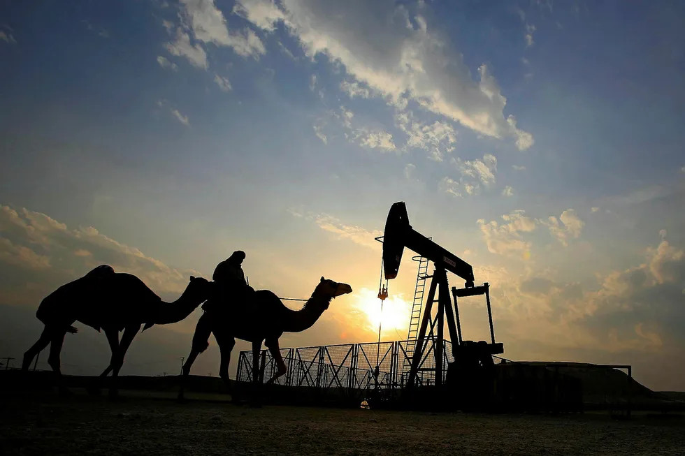Passing by: a man rides a camel through a desert oilfield in Bahrain