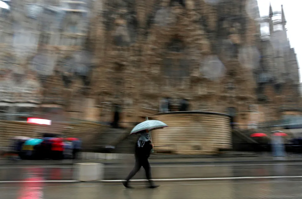 Weathering the storm: a woman shelters from the rain under an umbrella in Barcelona