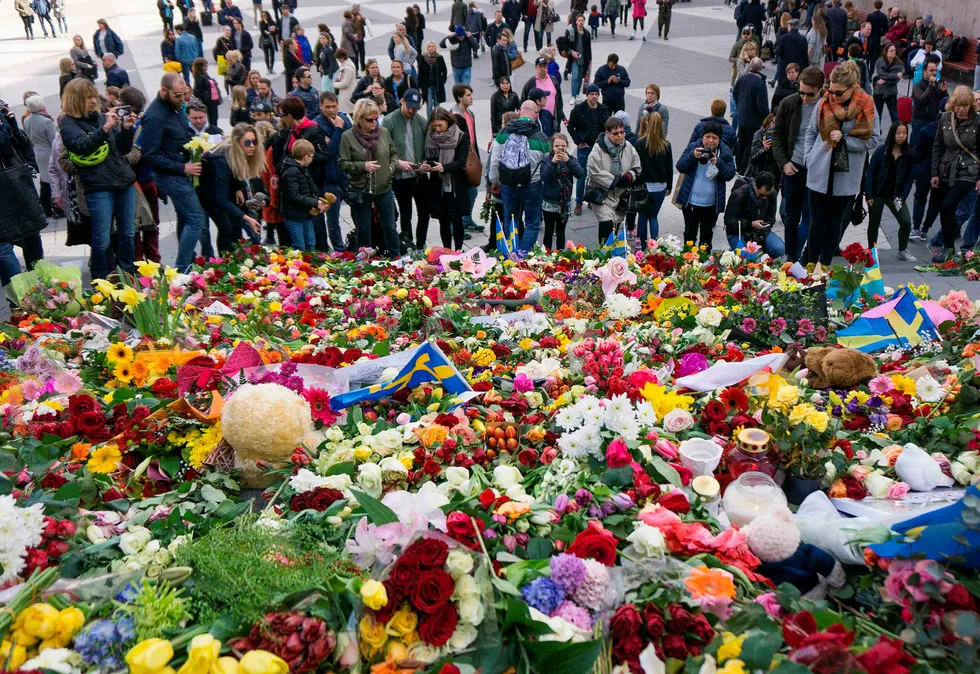 Folk samlet seg i dag ved blomsterhavet like ved stedet der en lastebil kjørte inn i en folkemengde i Stockholm fredag. Foto: JONATHAN NACKSTRAND/AFP Photo