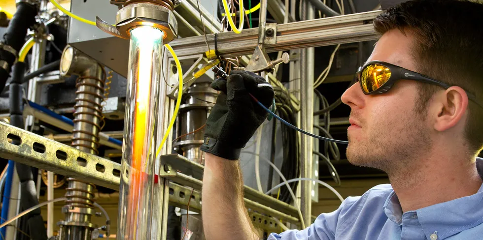 An H Quest engineer takes a spectral reading to measure the temperature of the reaction products. The glow is emitted by the white-hot carbon particles that were formed moments earlier within the high-speed flow of natural gas. Usually, this process is contained within steel tubes, but a clear tube was arranged for a photoshoot to make the process visible.