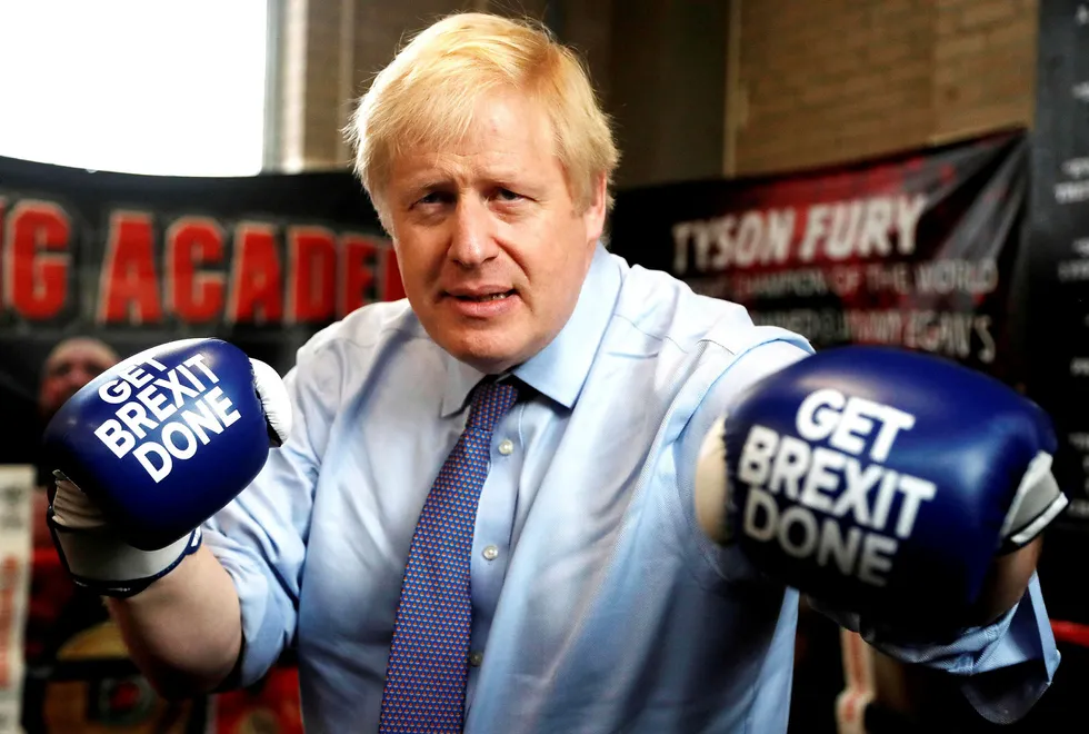 Statsminister Boris Johnson poserer med boksehansker utstyrt med «Get brexit done» under et valgkampstopp i en bokseklubb i Manchester.