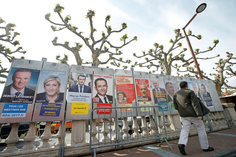 En mann går forbi valgplakater for de elleve kandidatene som stiller i det franske presidentvalget denne søndagen. Foto: Jean-Paul Pelissier/Reuters/NTB Scanpix