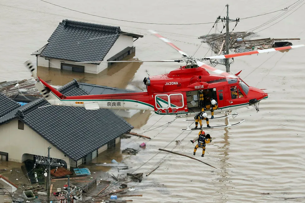 En beboer hentes opp fra et oversvømt område i Kurashiki i Okayama i Japan lørdag. Både båter og helikoptre tas i bruk i redningsarbeidet for å få hentet ut alle som er innestengt av vannmassene. Foto: Shohei Miyano / Kyodo News / AP / NTB scanpix