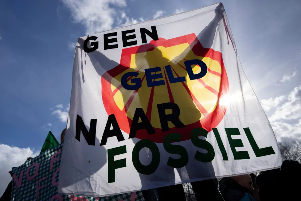 A protester holds a banner with the Shell logo reading “No Money To Fossil” during an Extinction Rebellion protest in The Hague, in March 2023.
