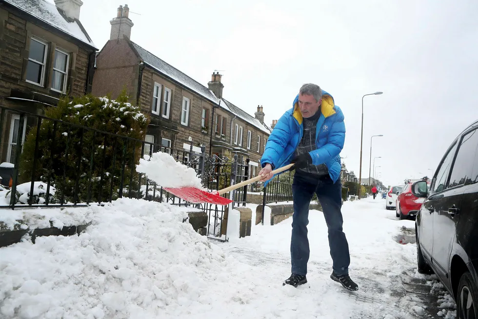 En mann spar snø utenfor sitt hjem i Portobello, Edinburgh. Snøvær og lave temperaturer har skapt problemer i hele Storbritannia, med fly som innstilles, tog som bryter sammen og passasjerer som strander i kulden i flere timer. Foto: Jane Barlow