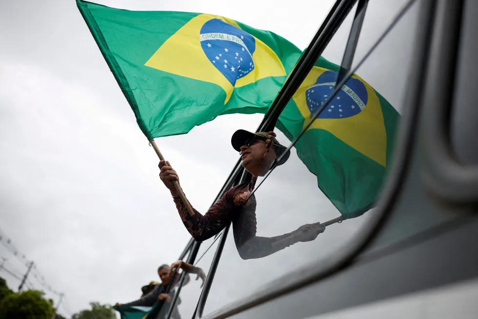Patriotic: a man holds a Brazilian flag from the window of a bus.