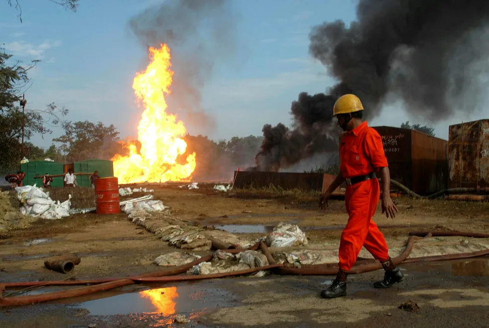 Earlier incident: a firefighter walks past a fire at one of OIL's oil wells in Dikom, Assam in 2005