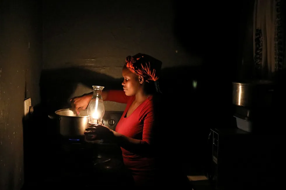 Lighting a path: A woman uses a paraffin light while cooking during an electricity load-shedding blackout in Soweto, South Africa