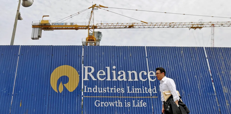 A man walks past an advertisement of Reliance Industries at a construction site in Mumbai, India