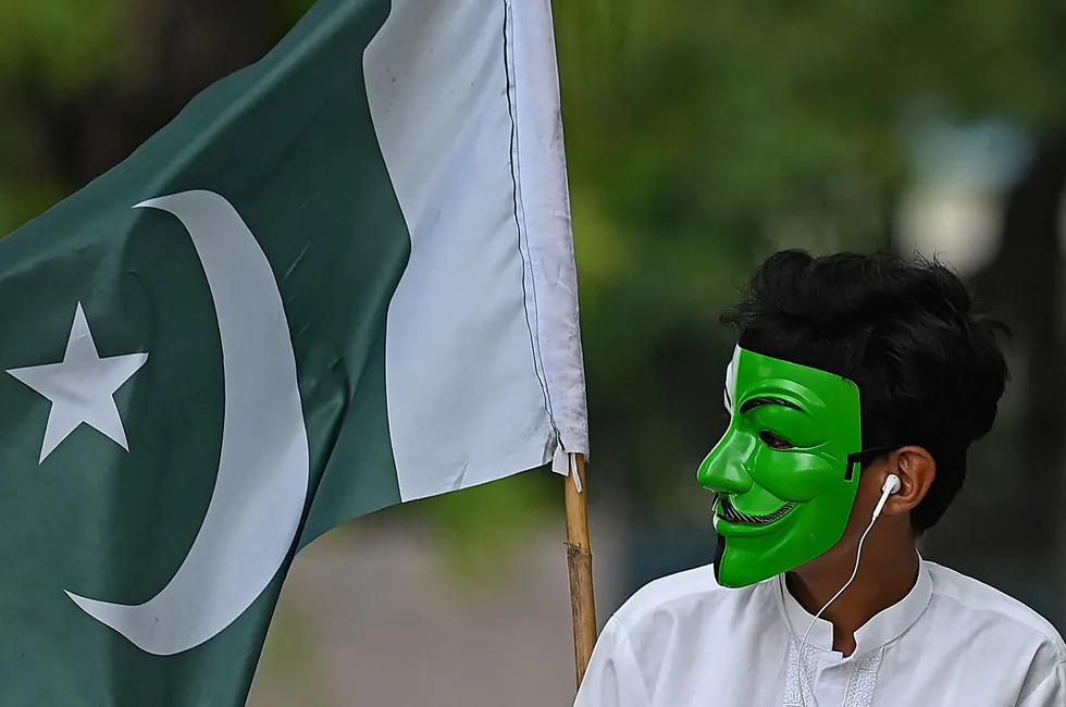 Growing market: A masked man stands next to Pakistan’s national flag at an Independence Day celebration in Islamabad.