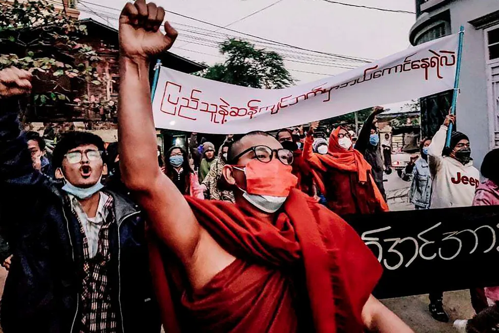 En buddhistisk munk hever den knyttede neven mens han marsjerte under et protestmøte mot militæret etter kuppet i Myanmar i fjor. Telenor-kunder i Myanmar som er regimekritikere frykter konsekvenser ved et salg av mobilvirksomheten.