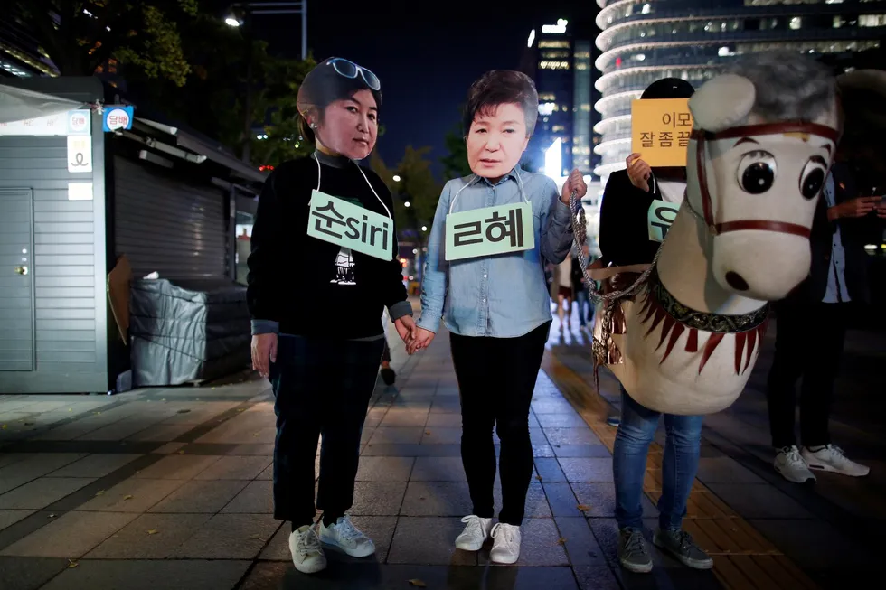 Protestanter i Seoul bærer plakater om å få fjernet president Park Geun-hye. I stedet har presidenten svart med å fjerne statsministeren og finansministeren. Maske med bilde av presidenten bæres av protestanten i midten. Foto: Kim Hong-Ji/Reuters/NTB scanpix