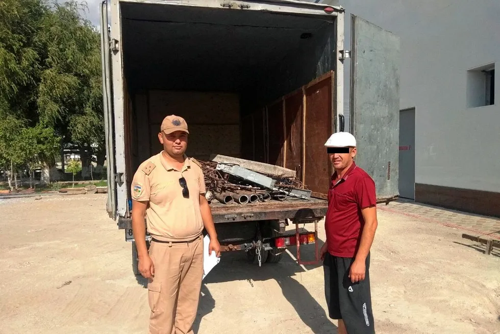 Heavy evidence: a National Guard officer and a shop owner standing in front of recovered gas pipes that had been stolen from the Uchkir field in Uzbekistan