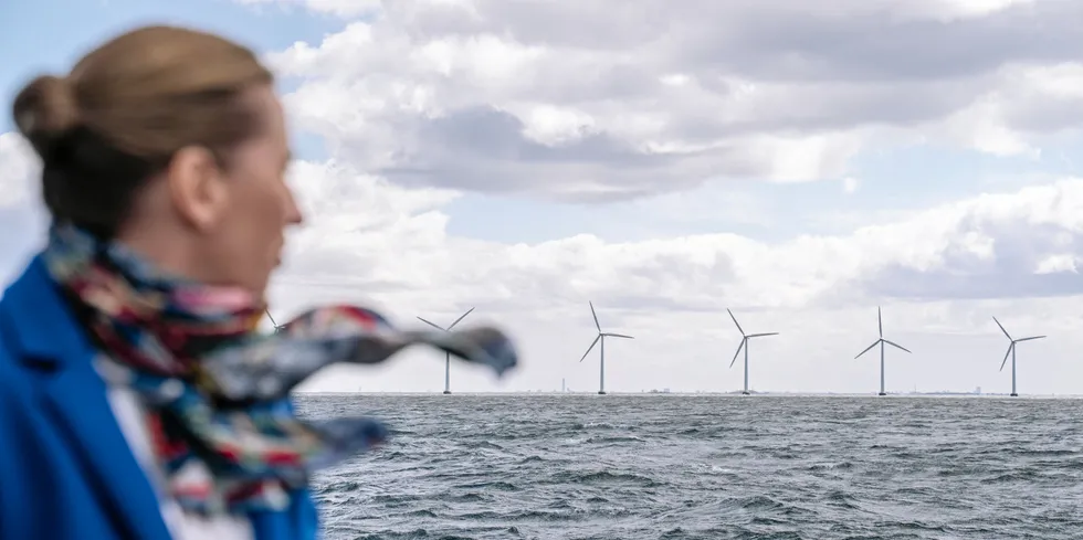 Denmark's Prime Minister Mette Frederiksen standing on a boat looks towards the wind turbines of the Middelgrunden offshore wind farm.