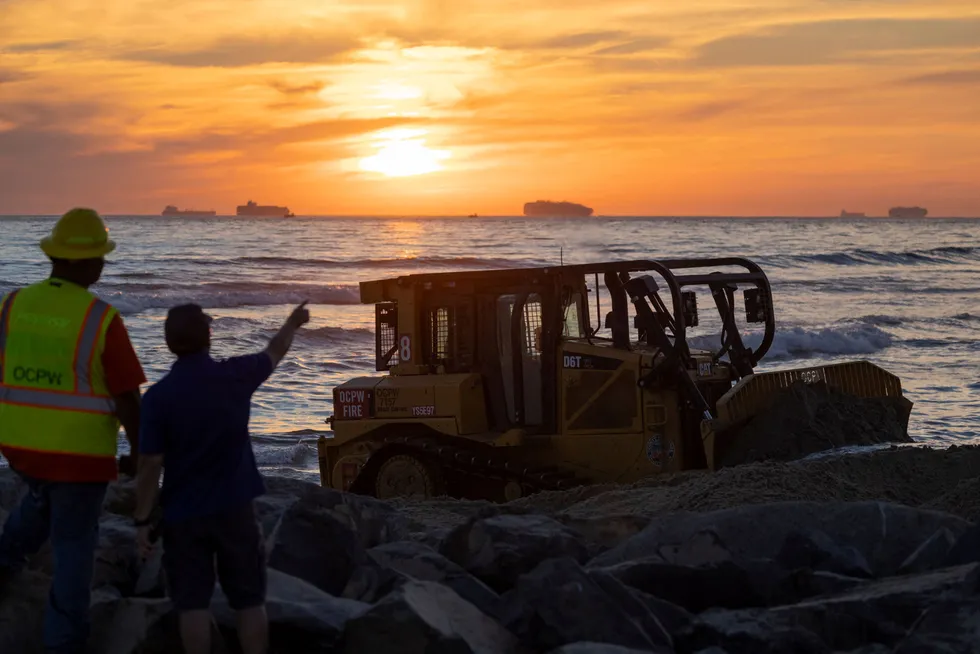Line of defense: Heavy equipment is used in Orange County, California at sunset to block an oil spill in the ocean from reaching the Talbert Marshlands.