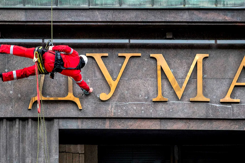 Turnaround: a worker cleans letters above the entrance to the Duma in Moscow
