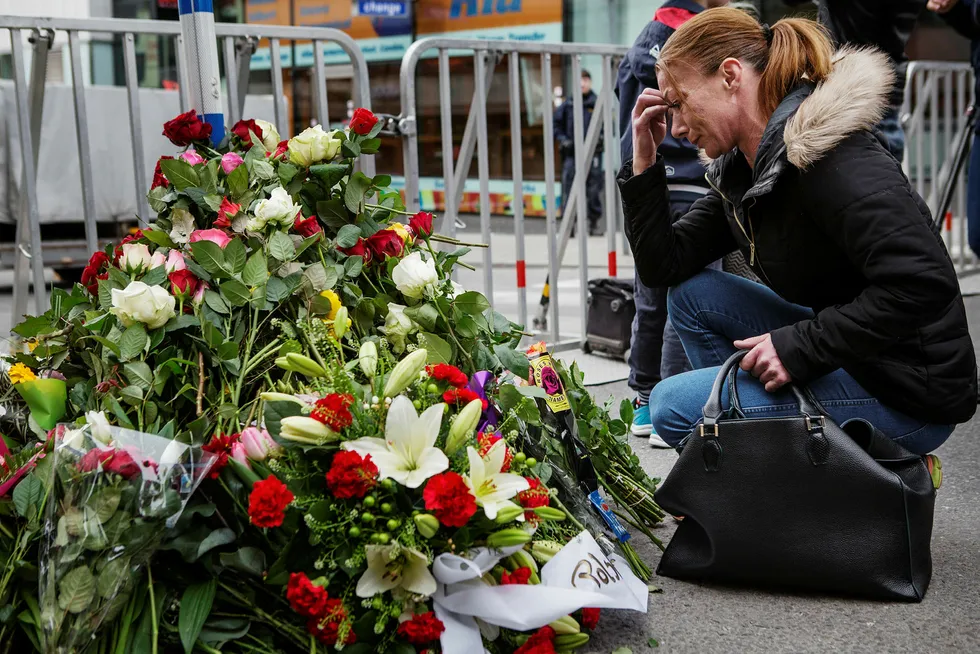 Erika Angermund legger ned blomster foran sperringen like ved Åhléns-varehuset i Drottninggatan. Hun har tatt turen til byen med familien for å ta del i sorgen. Foto: Linus Sundahl-Djerf
