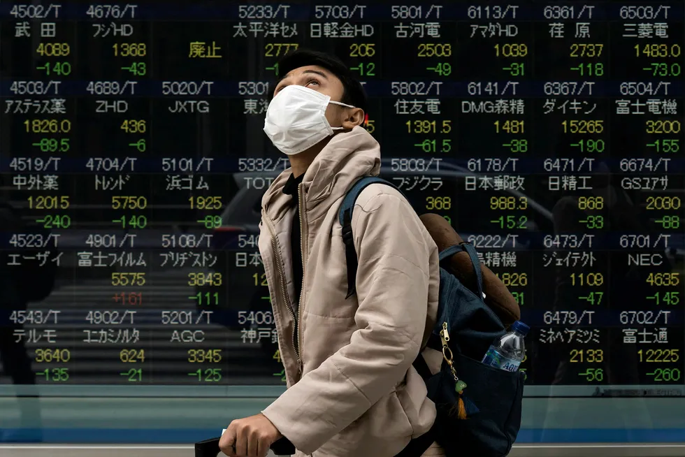 En fotgjenger går forbi Nikkei i Tokyo som falt mer enn 3,5 prosent da den åpnet mandag.