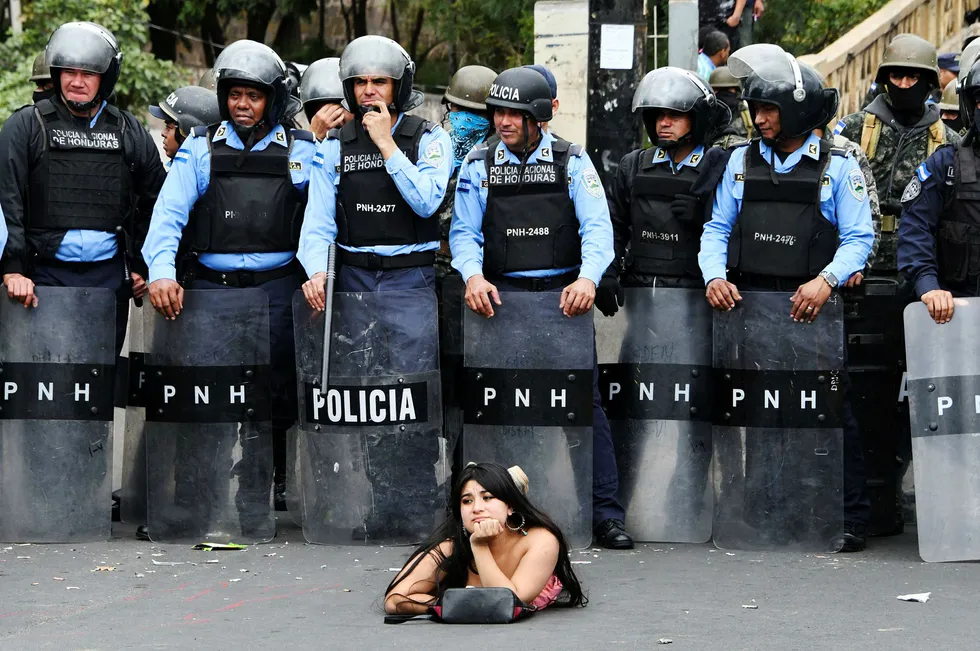 A supporter of the presidential candidate for the Honduran Opposition Alliance Against the Dictatorship for the past election, Salvador Nasralla, lies on the street in front of police officers during a demonstration against the contested re-election of President Juan Orlando Hernandez, in Tegucigalpa on January 21, 2018. The opposition called for a "national strike" on Saturday to focus on blocking the country's main roads ahead of the start of the president's new term in office on January 27. Dozens of people have been killed and hundreds jailed since Hernandez was declared the winner of the November 26 run-off election -- but only after a three week stretch of often-interrupted ballot counting that stoked tensions and sparked accusations of fraud in the Central American country. / AFP PHOTO / Orlando SIERRA --- Foto: ORLANDO SIERRA/AFP/NTB scanpix