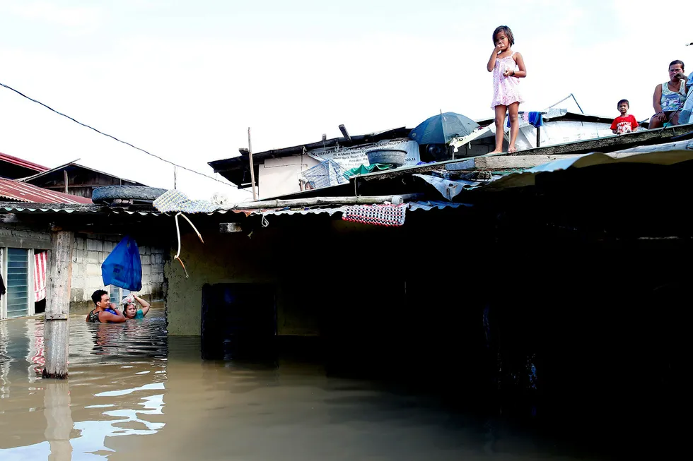 Et par tar seg gjennom vannmassene for å kjøpe drikkevann etter at tyfonen Mangkhut rammet Filipinene i helgen og oversvømmet lavtliggende områder. Bildet er fra Calumpit i Bulacan-provinsen nord for Manila.
