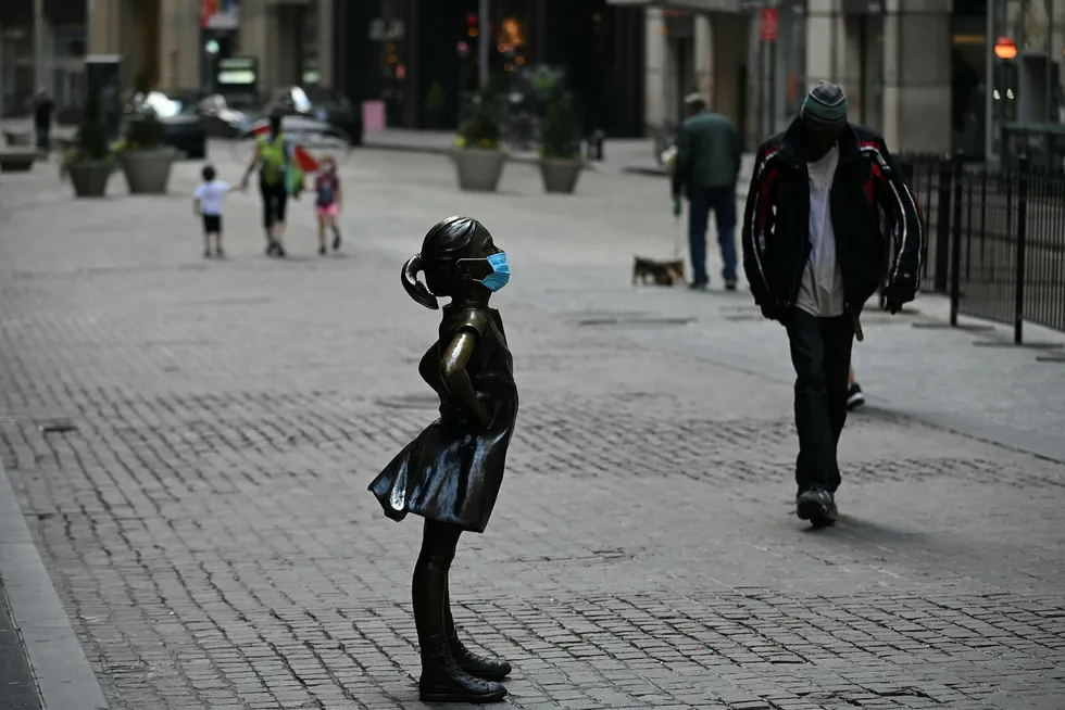 På Wall Street står bronseskulpturen «Den fryktløse piken» rett foran inngangen til New York-børsen, for anledningen med ansiktsmaske.